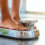 person weighing themselves on a scale